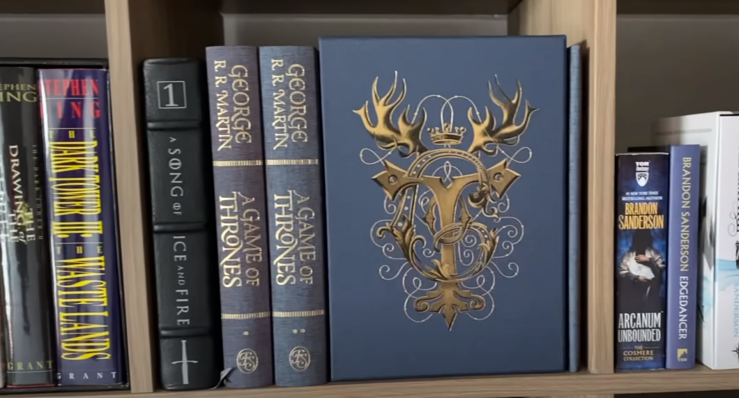 Books from the Game of Thrones series on a shelf alongside other books