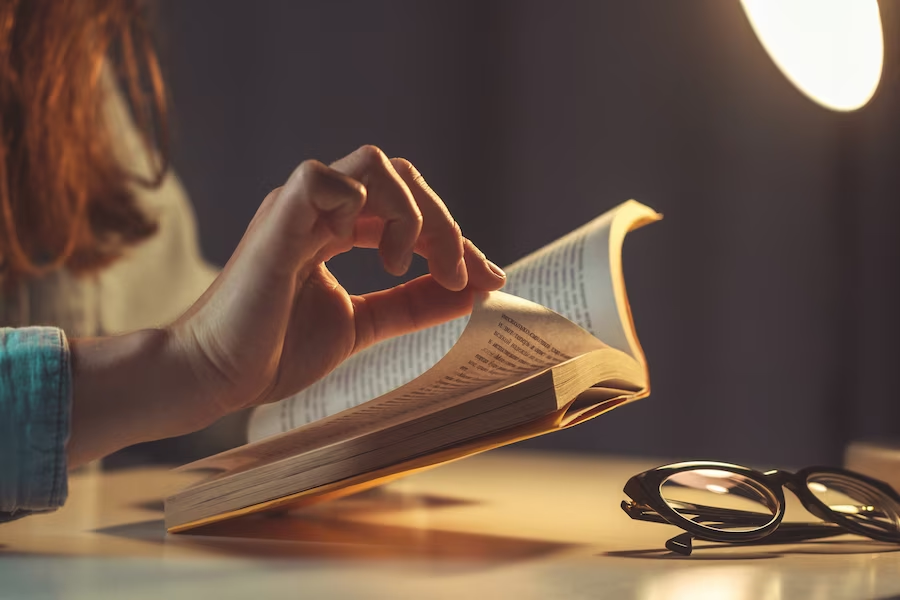 Woman Reading a Book and Turning a Page